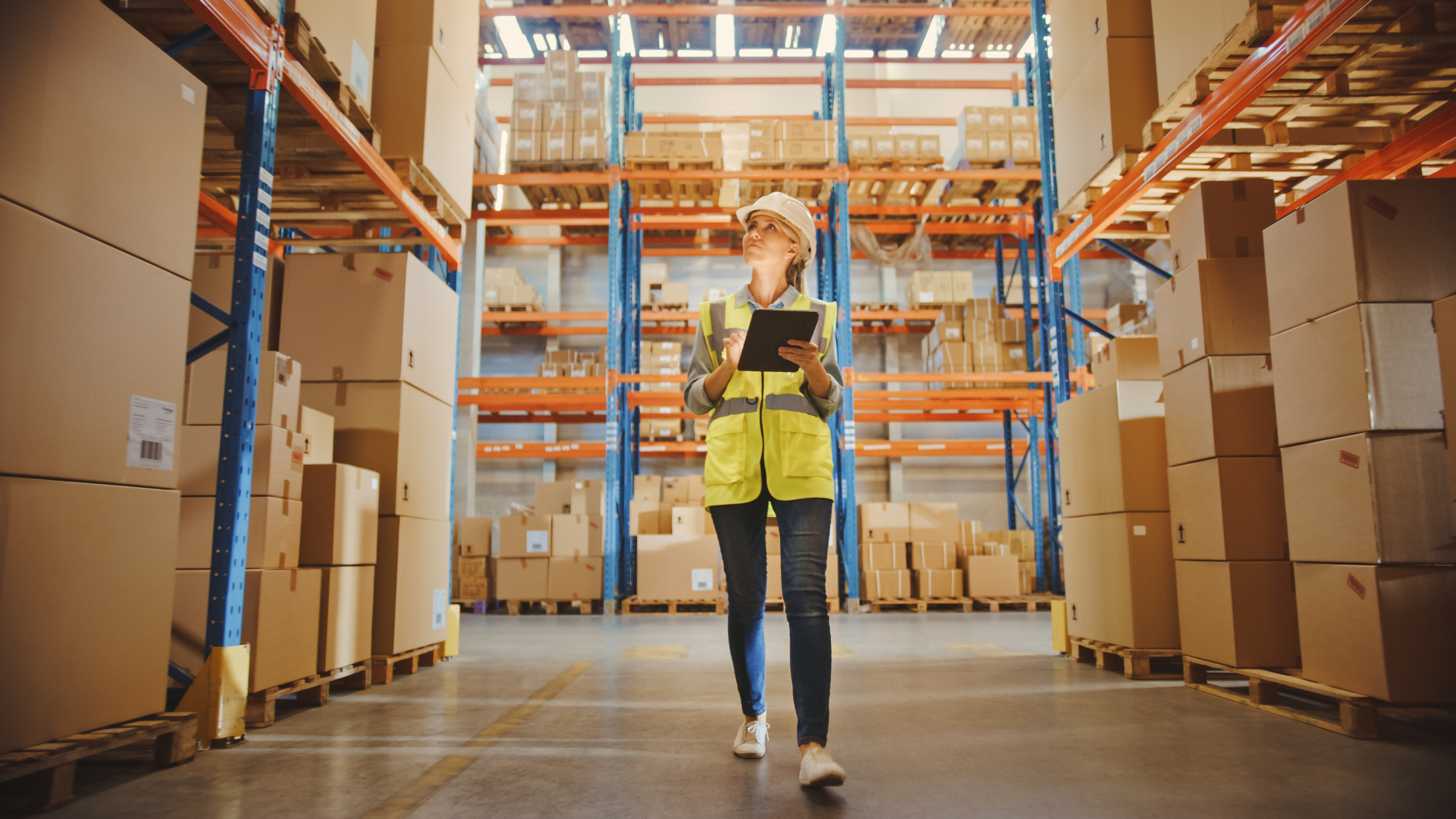 Kvinna går i ett lager och skriver ner warehouse optimization tips